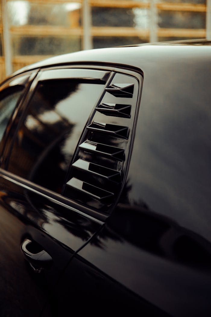 Close-up of a black car's side window with modern louvers, showcasing sleek design.